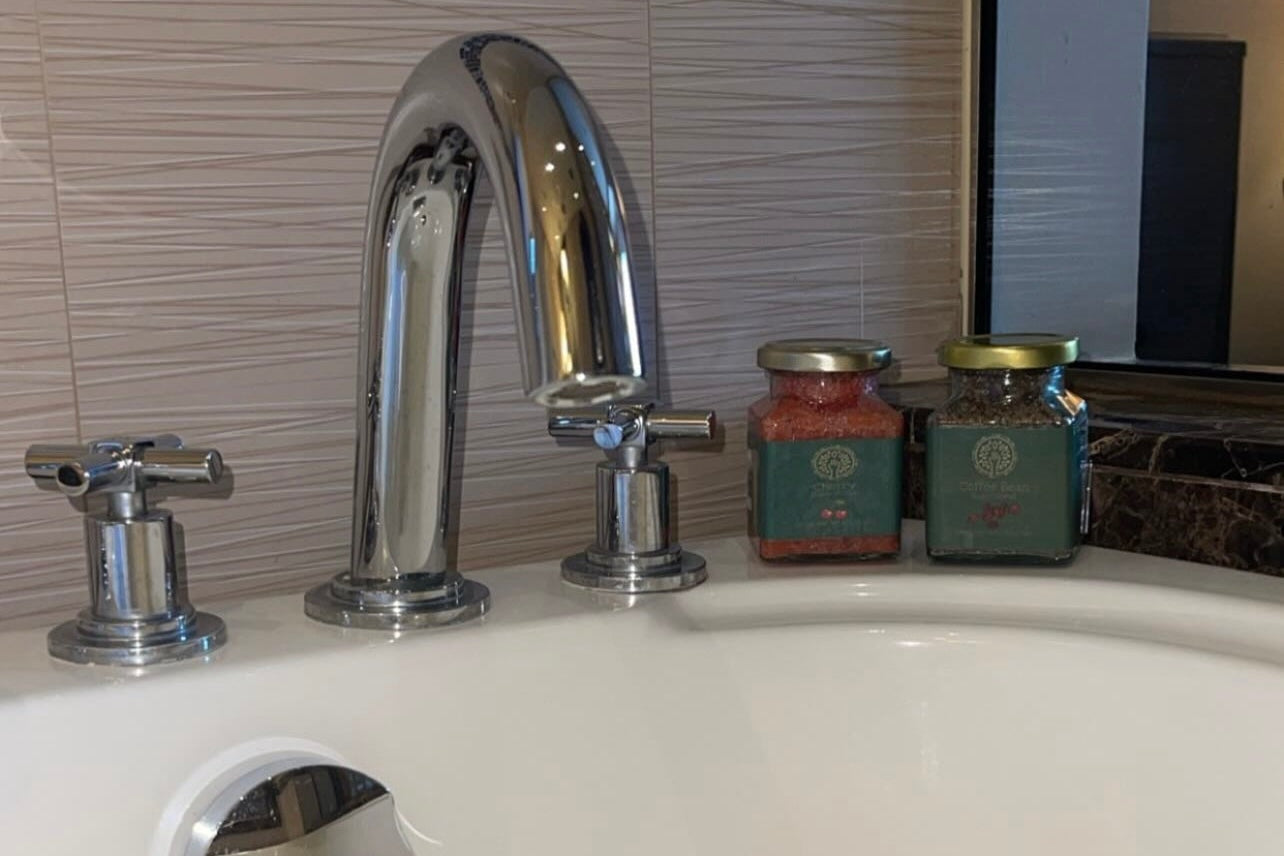 Chrome faucet on a white bathtub with tiled wall in the background